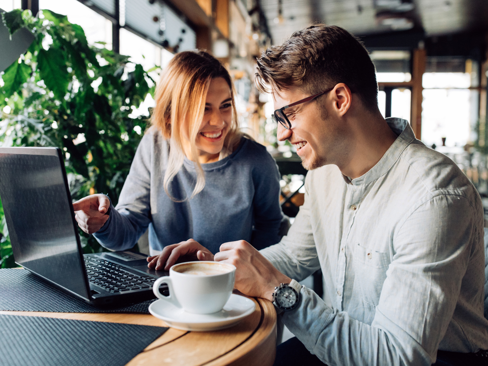 happy woman and man looking at website over coffee