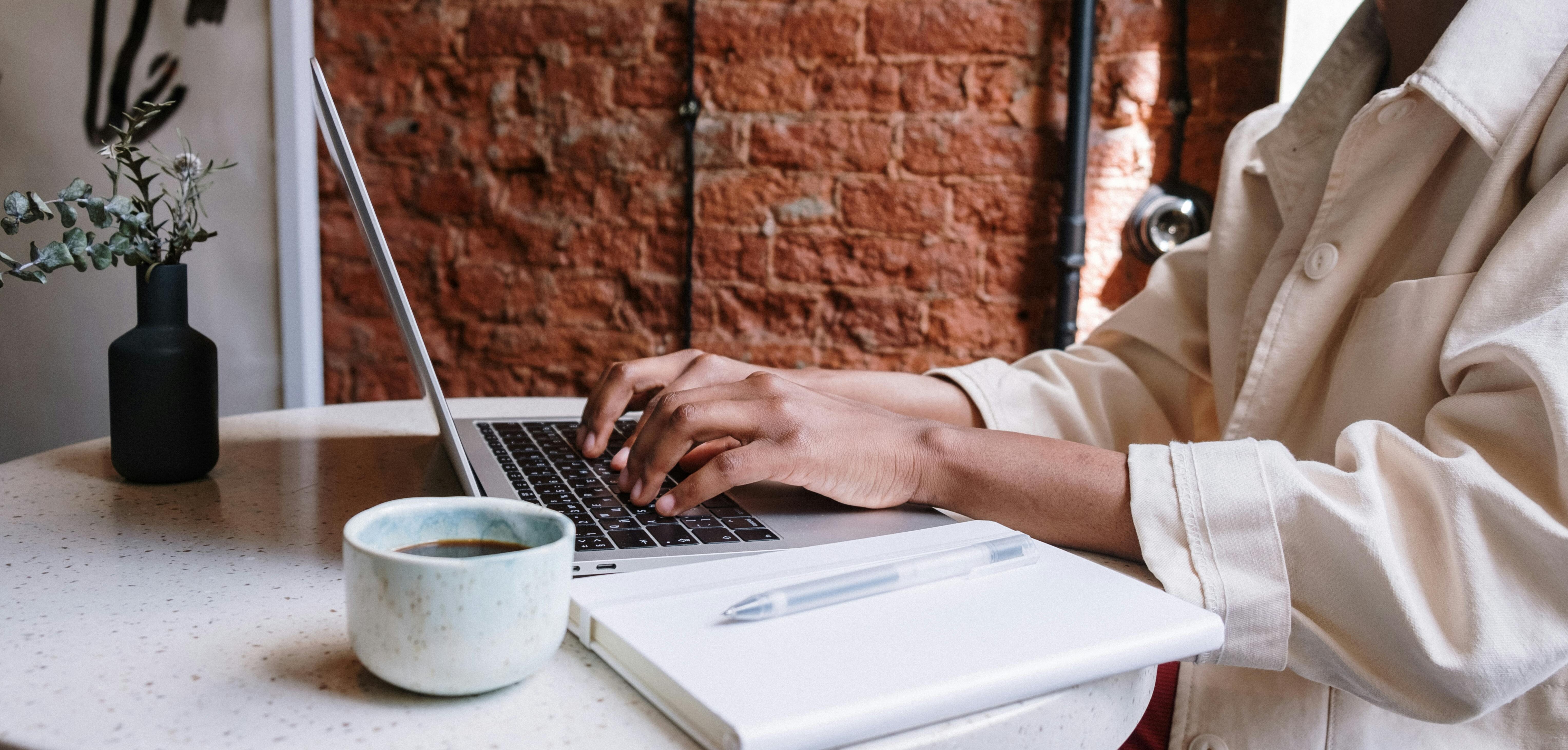 Woman working on a laptop with coffee in a cozy café, highlighting a productive and modern vibe.